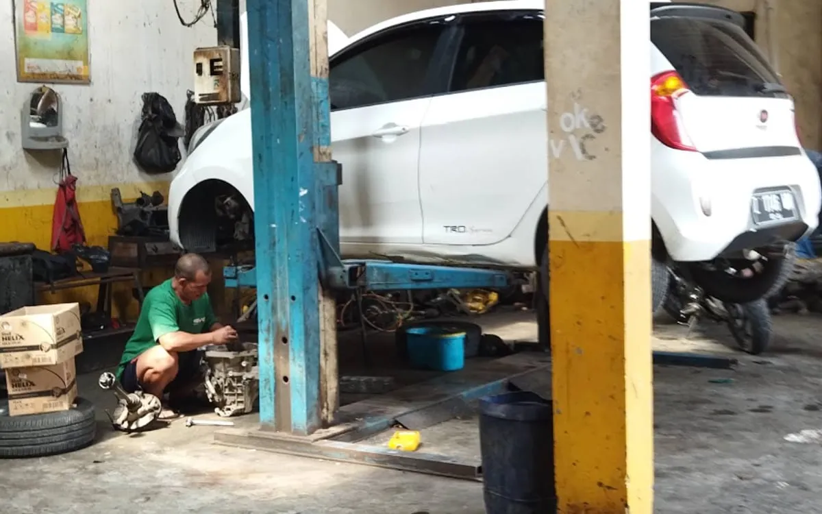 Mekanik mengerjakan mobil di atas lift di area servis Sinar Surya Auto Care Bojongsoang