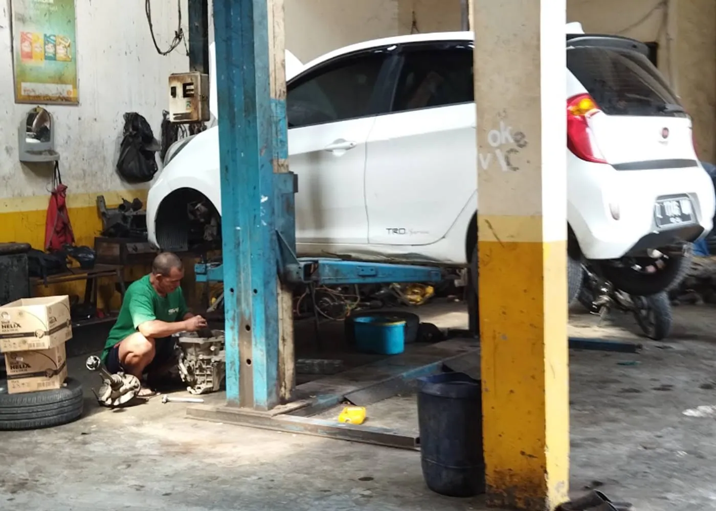 Mekanik Sinar Surya Auto Care mengerjakan mobil di atas lift di area servis bengkel Bojongsoang